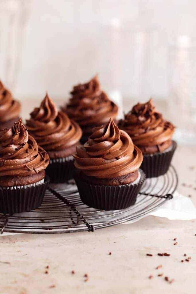 chocolate cupcakes with chocolate frosting on a circular wire cooling rack
